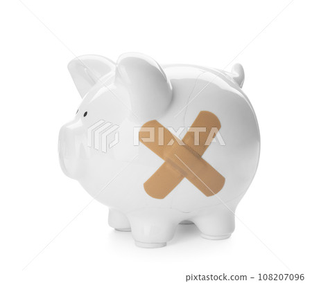 Piggy bank with sticking plasters isolated on white Piggy bank with sticking plasters isolated on white 108207096