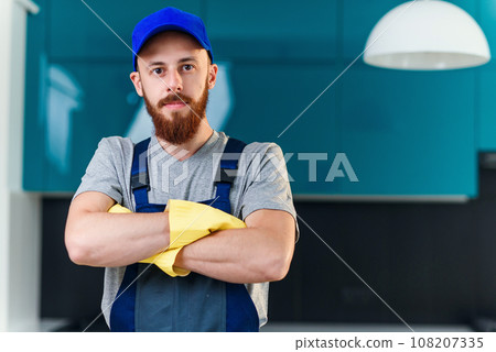 Professional male worker from cleaning service in special uniform folded his arms on the background of the contemporary cuisine. 108207335