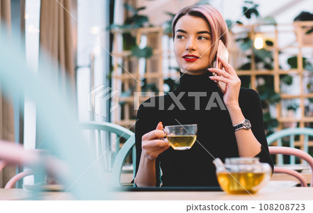 Trendy content modern woman talking on phone at cafe Trendy content modern woman talking on phone at cafe 108208723