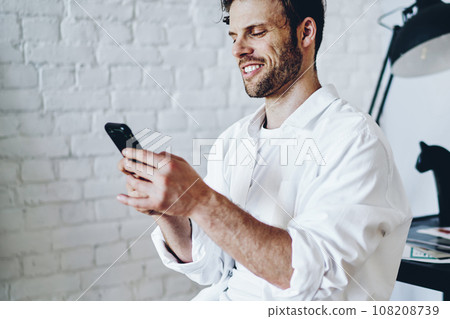 Cheerful caucasian man satisfied with tariffs for 4G internet connection on mobile phone Cheerful caucasian man satisfied with tariffs for 4G internet connection on mobile phone 108208739