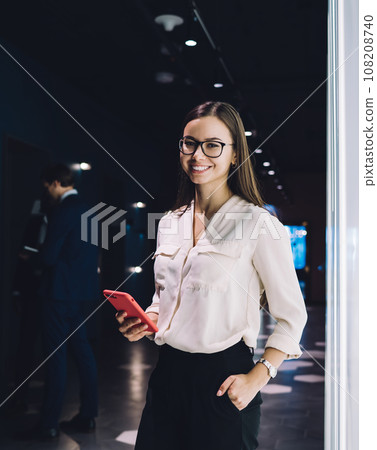 Happy confident businesswoman using smartphone in contemporary office building Happy confident businesswoman using smartphone in contemporary office building 108208740