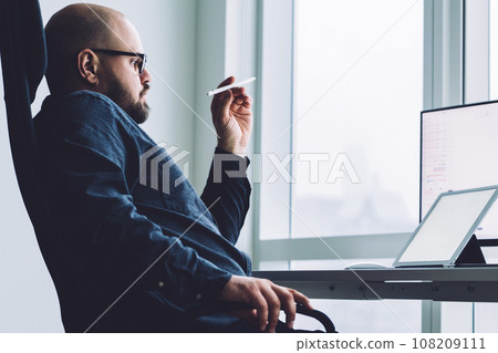 Pensive man with devices at office desk 108209111