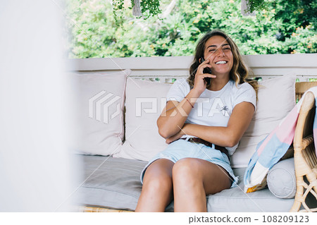 Cheerful woman having phone conversation on terrace Cheerful woman having phone conversation on terrace 108209123