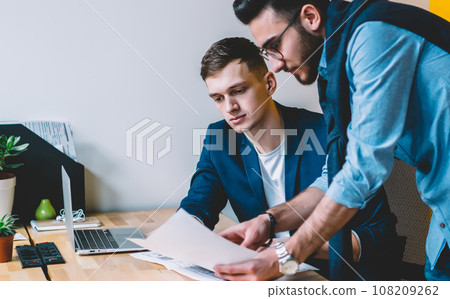 Young man showing papers to colleague Young man showing papers to colleague 108209262