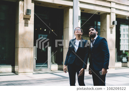 Colleagues in suits looking up in city Colleagues in suits looking up in city 108209322