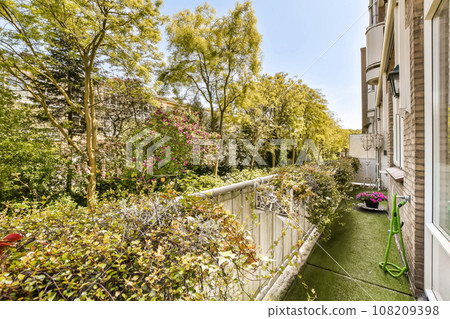 an outside view of the back yard with plants and trees in blooming pots on either side of the house 108209398