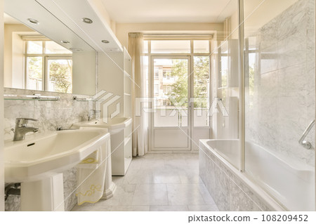 a bathroom with marble flooring and white fixtures on the walls, two sinks in the bathtub is next to the shower a bathroom with marble flooring and white fixtures on the walls, two sinks in the bathtub is next to the shower 108209452
