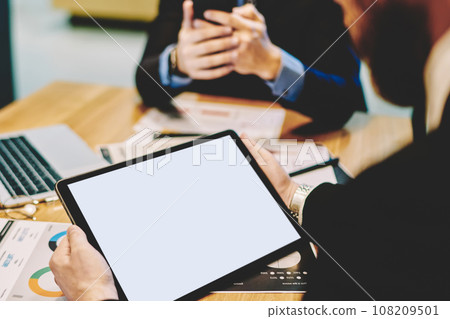 Faceless office worker watching tablet during business meeting 108209501