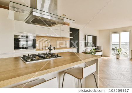 a modern kitchen with wood counter tops and white cabinets in the room is very open to the view from the window 108209517