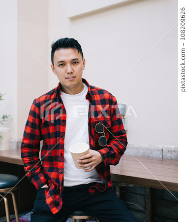 Calm adult ethnic man having hot drink while sitting and taking refreshment on terrace Calm adult ethnic man having hot drink while sitting and taking refreshment on terrace 108209626