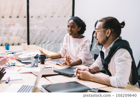 Adult multiracial coworkers brainstorming during conference in office Adult multiracial coworkers brainstorming during conference in office 108209640