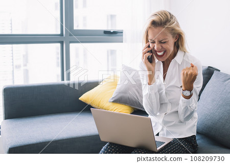 Young blonde screaming with joy while talking on phone Young blonde screaming with joy while talking on phone 108209730