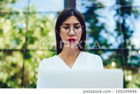 Young Spanish student in optical glasses making online research of digital Young Spanish student in optical glasses making online research of digital 108209846