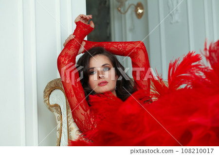 Perfect sensual brunette woman with makeup and wavy hair in marsala red dress resting 108210017