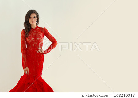 Beauty woman with earrings and red lip makeup wearing red evening gown  108210018