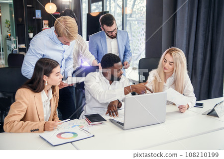 Multiethnic group young business colleagues having meeting about their business project and comparing data from different reports and table laptop. 108210199