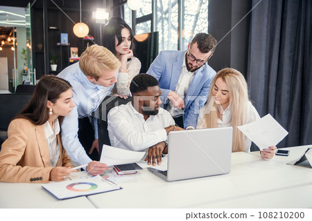 Multiethnic group young business colleagues having meeting about their business project and comparing data from different reports and table laptop. Multiethnic group young business colleagues having meeting about their business project and comparing data from different reports and table laptop. 108210200