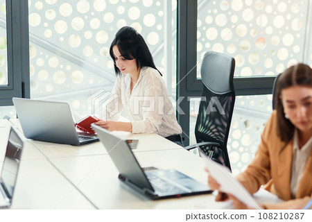Caucasian female office worker using laptop while sitting at her desk. Caucasian female office worker using laptop while sitting at her desk. 108210287