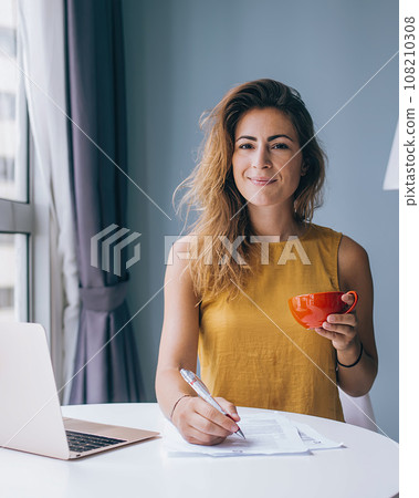 Portrait of positive attractive woman enjoying break for drinking tea during accounting financial budget 108210308