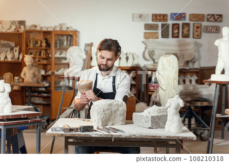 Stone carver works with wooden hammer and chisel at limestone. Stone carver works with wooden hammer and chisel at limestone. 108210318