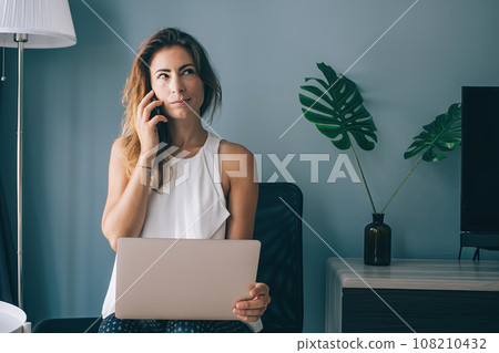 Coquettish woman with laptop talking on phone Coquettish woman with laptop talking on phone 108210432