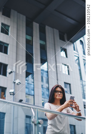 hipster girl using internet connection in roaming on cellphone looking at camera on street 108210542