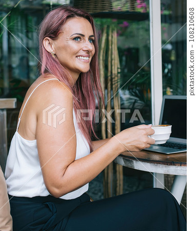 Modern businesswoman drinking coffee and working on laptop 108210608