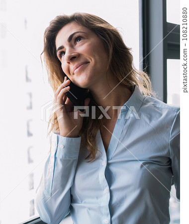 Content lady having conversation on phone nearby window Content lady having conversation on phone nearby window 108210880