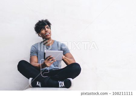 Smiling black man with legs crossed using laptop 108211111
