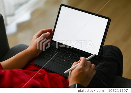 Casual male freelancer sitting on sofa in living room and working online on digital tablet Casual male freelancer sitting on sofa in living room and working online on digital tablet 108211397