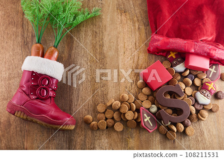 Dutch holiday Sinterklaas background. Children shoe with carrots, traditional sweets and chocolate letter 108211531