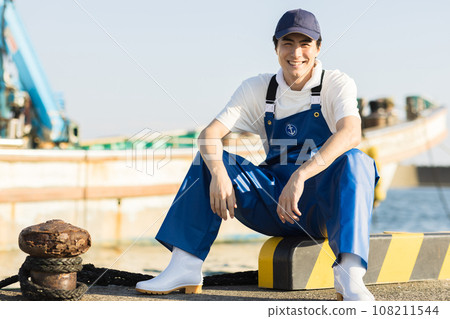 A young fisherman working at a fishing port 108211544