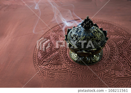 Smoke from burning incense sticks on brown decorative background 108211561