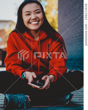 happy cheerful hipster girl with cellphone in hands enjoying leisure outdoors, generation happy cheerful hipster girl with cellphone in hands enjoying leisure outdoors, generation 108211638