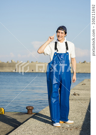 A young fisherman working at a fishing port 108211692