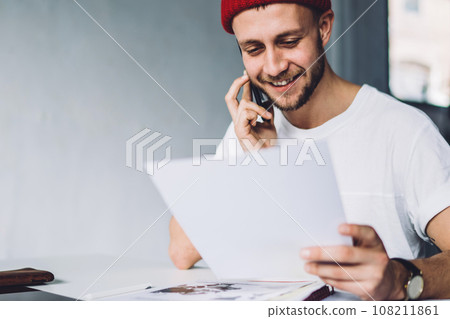 Content hipster male with paper talking on phone 108211861