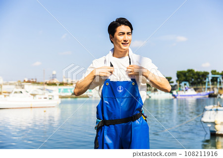 A young fisherman working at a fishing port 108211916