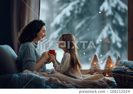 Mother and daughter enjoying winter nature in the window Mother and daughter enjoying winter nature in the window 108212024