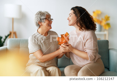 woman and her senior mother with autumn leaves 108212147
