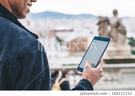Ethnic cheerful male using tablet on street Ethnic cheerful male using tablet on street 108212152