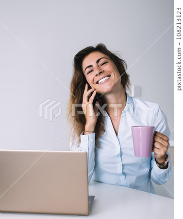 Excited worker talking on phone having coffee Excited worker talking on phone having coffee 108213123