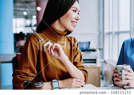 happy pretty female employees talking to each other during coffee break in office 108213153