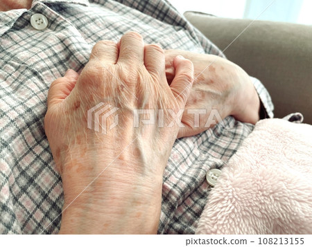 Hand of a senior woman wearing pajamas holding her chest 108213155