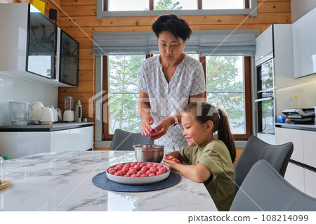 Grandmother and granddaughter preparing meatballs. Grandmother and granddaughter preparing meatballs. 108214099