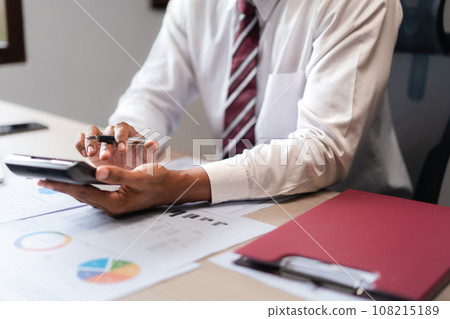 Businessman use calculator to calculate cost of project and checking marketing document of startup Businessman use calculator to calculate cost of project and checking marketing document of startup 108215189