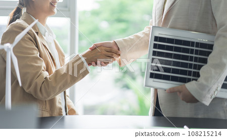 Alternative energy environment businesspeople shake hands after deal about solar cell panel project 108215214