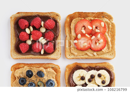 Sweet toasts with raspberries, banana, strawberries, blueberries on light background. Flatly. 108216799
