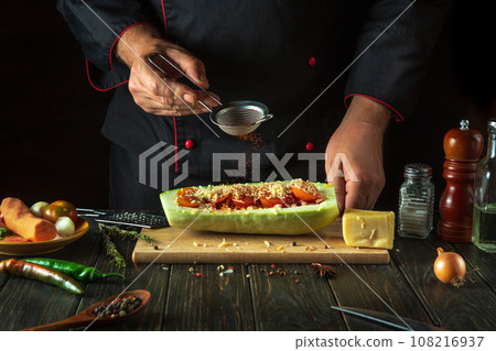 The chef adds paprika to the zucchini on the kitchen table. The concept of cooking national stuffed zucchini or mahshi for dinner 108216937