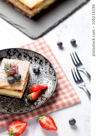 A piece of Napoleon cake with poppy seeds and cherries 108218190