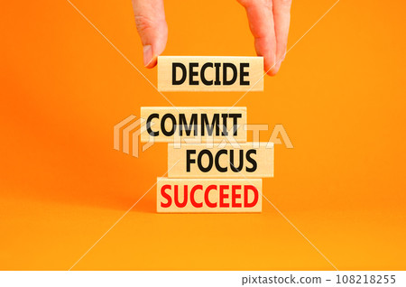Decide commit focus succeed symbol. Concept word Decide Commit Focus Succeed on wooden block. Beautiful orange background. Businessman hand. Business decide commit focus succeed concept. Copy space. 108218255